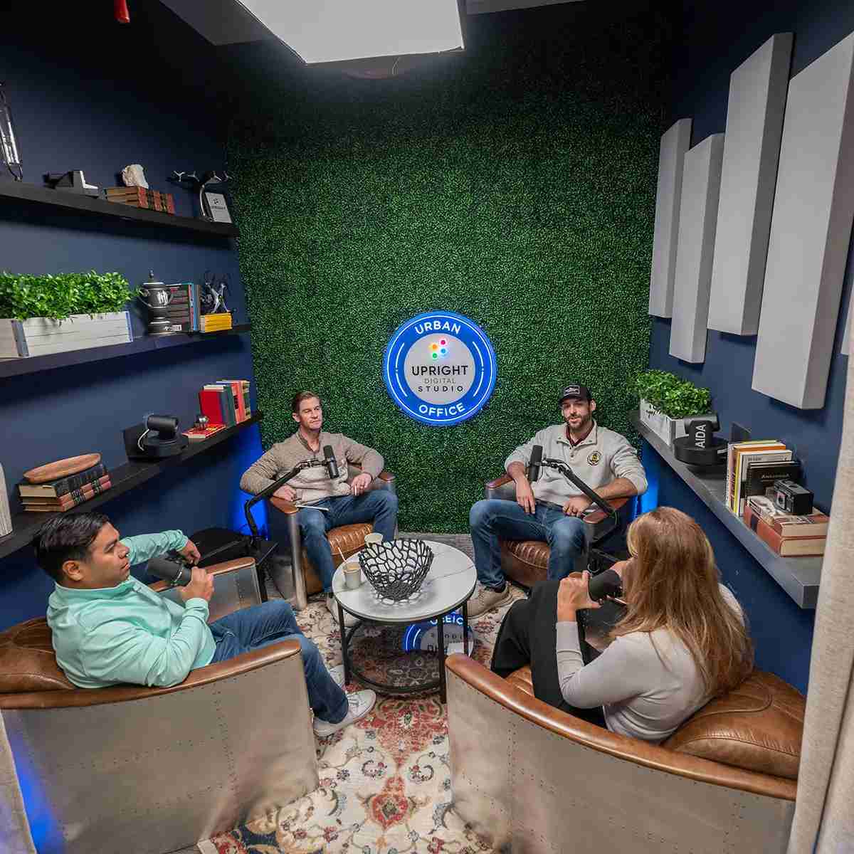 A group of people seated in chairs, engaged in discussion in a podcast room in Houston, TX