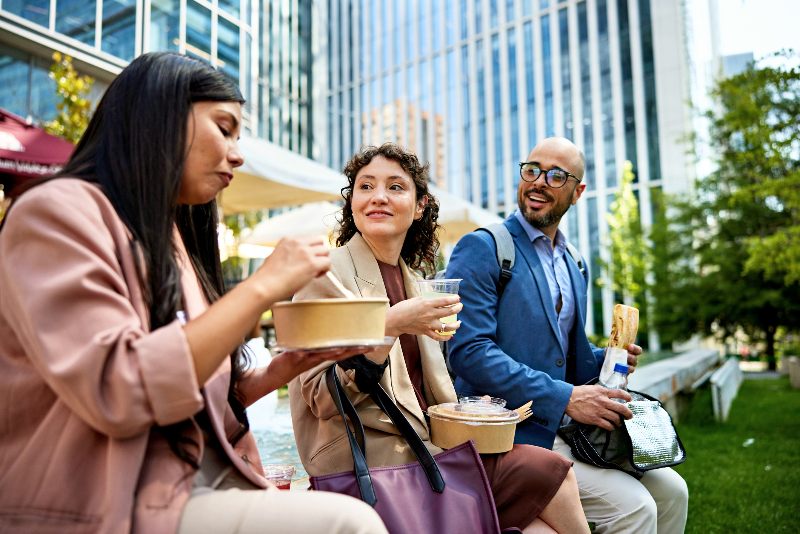 Coworkers eating lunch together outside by Urban Office