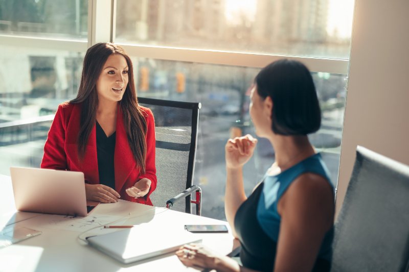 Two women talking with laptops by Urban Office in Houston and San Antonio