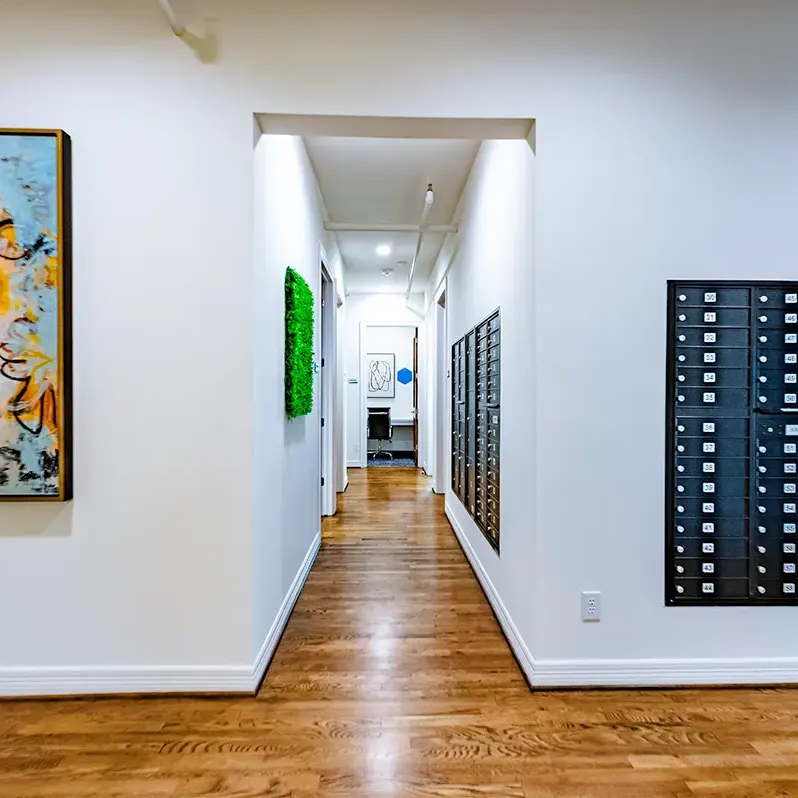 A hallway, displaying a painting on the wall alongside beautiful wooden floors in Houston, TX