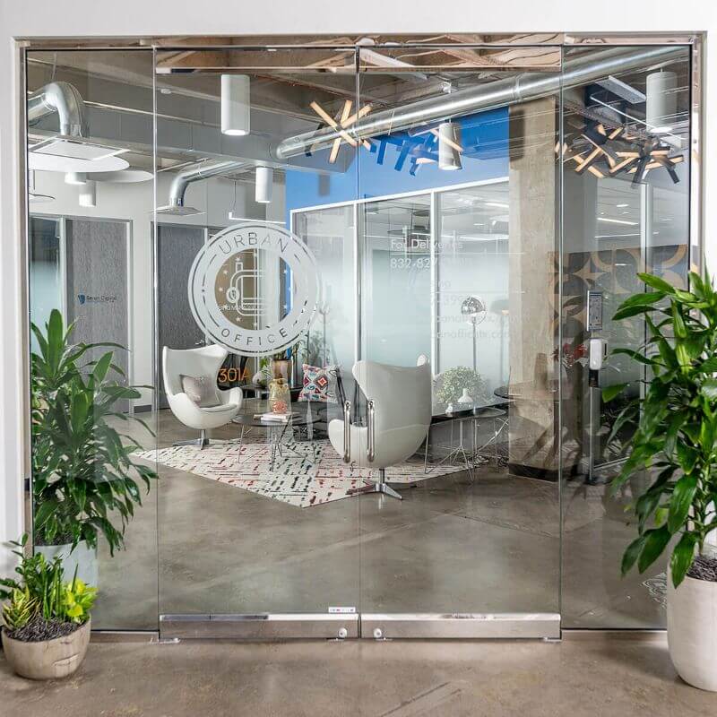 Glass-walled office in Houston, TX, featuring plants and chairs for a modern workspace