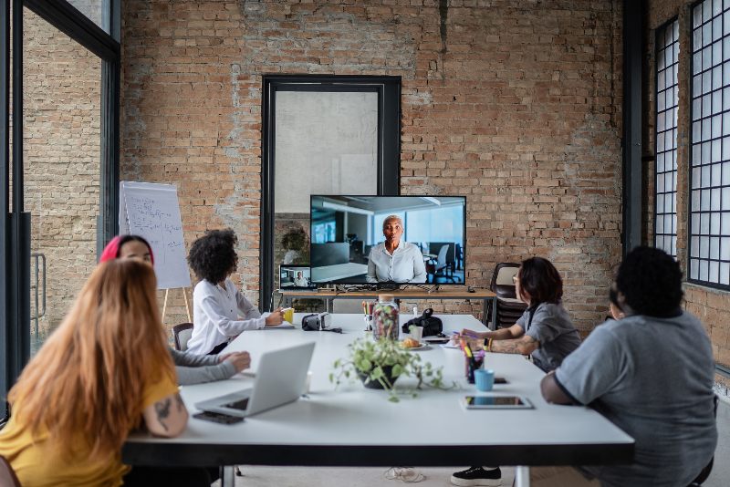 Group of people around a table looking at a monitor in a shared meeting room by Urban Office