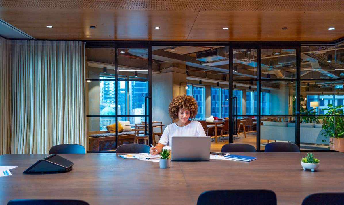 A woman sits at a table with a laptop, focused on her work in Houston, TX