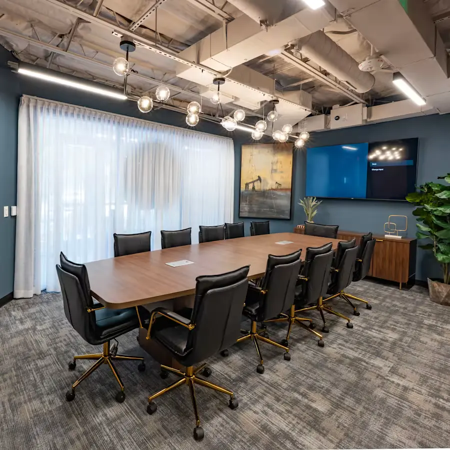 Conference room with large table and 12 chairs and a wall mounted TV in the background in River Oaks, Houston, Texas