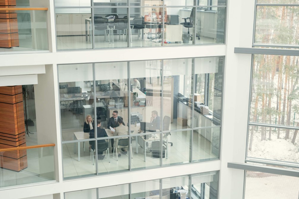 Modern corporate office building with glass walls and employees meeting in a conference room