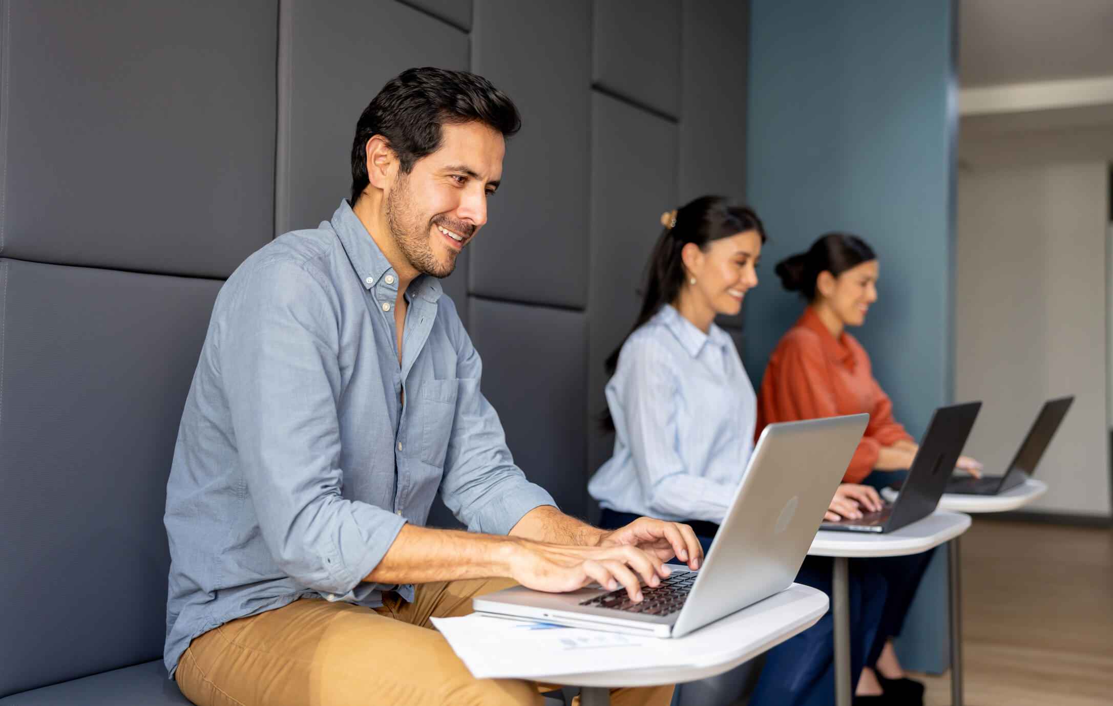 Three people sitting on a bench with laptops engaged in work in Houston, TX