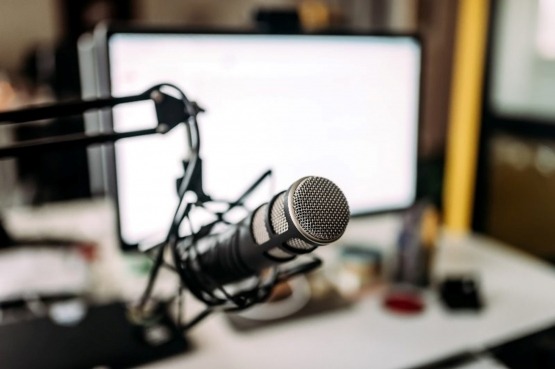 A microphone positioned in front of a computer monitor, set in a workspace in San Antonio, TX